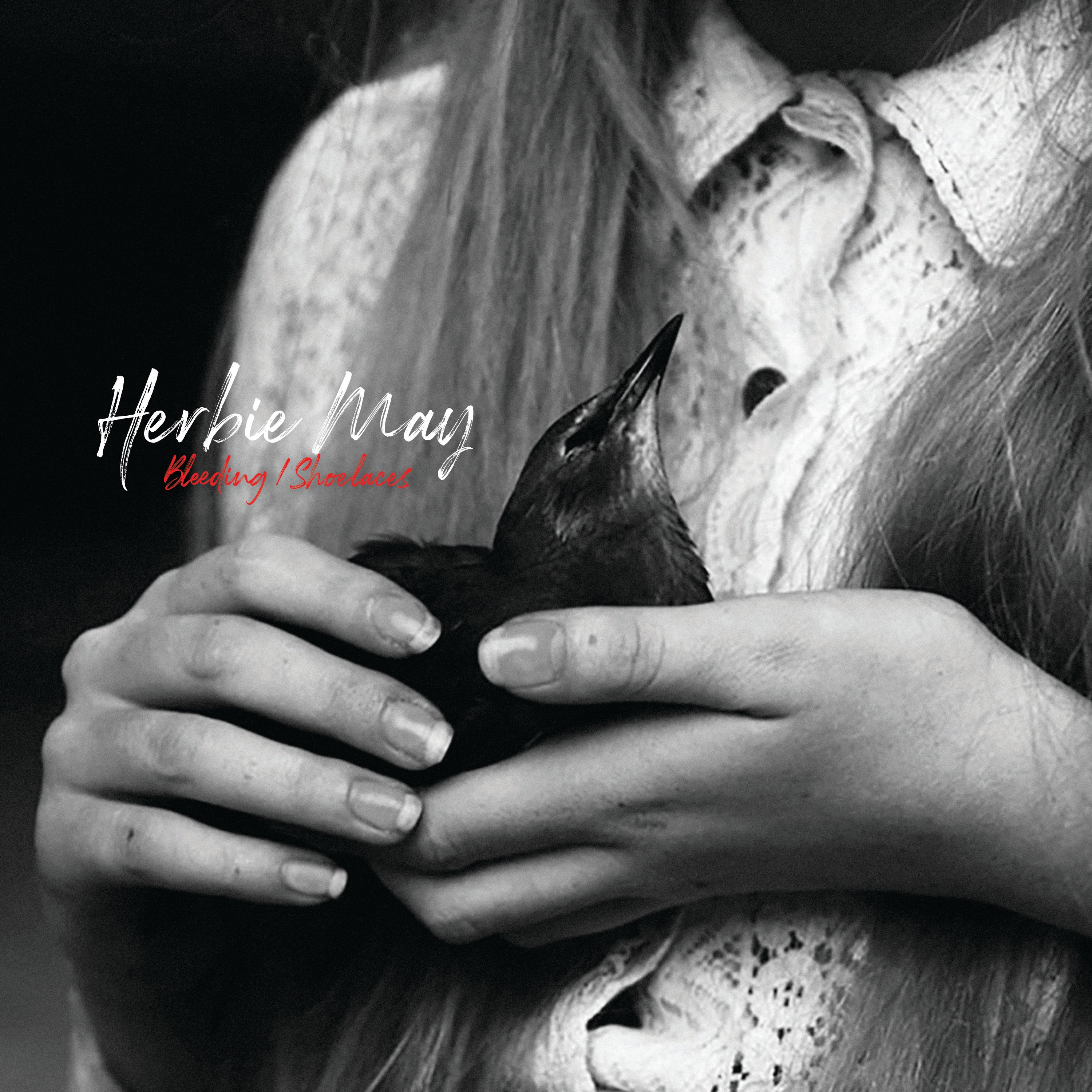 Front cover image of Herbie May's first solo single, Bleeding/Shoelaces. A black and white image of a womans hands gently holding a young bird.
